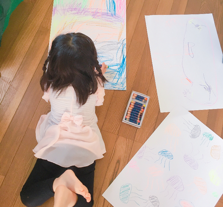 画用紙にクレヨンで絵を描いてる子供