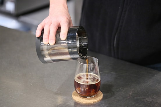 G-PRESSOが熱を使わずに遠心力だけで高濃度抽出したコーヒーをコップに注ぐ
